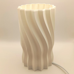 Une lampe cylindrique sculptée d'une hélice douce, pour une lumière originale et enveloppante.