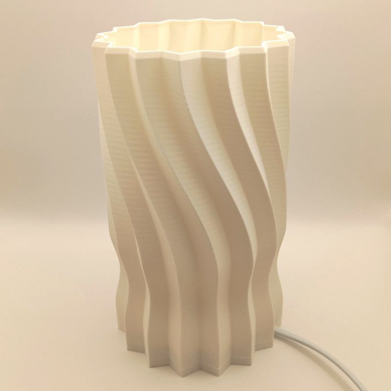 Une lampe cylindrique sculptée d'une hélice douce, pour une lumière originale et enveloppante.