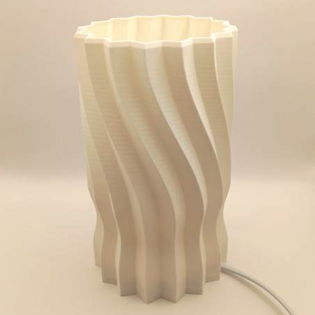 Une lampe cylindrique sculptée d'une hélice douce, pour une lumière originale et enveloppante.