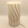 Une lampe cylindrique sculptée d'une hélice douce, pour une lumière originale et enveloppante.